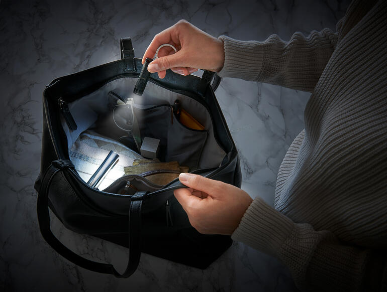 Deux mains tenant une lampe de poche micro intelligente dans un sac