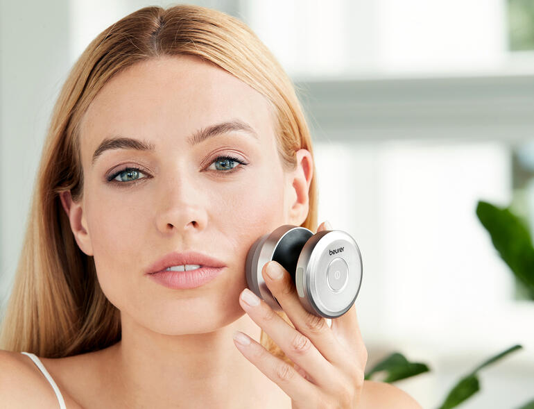 Brosse du visage duale en utilisation, femme tenant la brosse contre son visage.