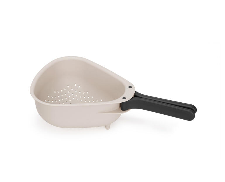 Passoire de cuisine gain de place beige avec un manche noir sur fond blanc.