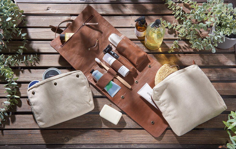 Trousse de toilette en cuir de buffle avec divers produits de soin sur une table.
