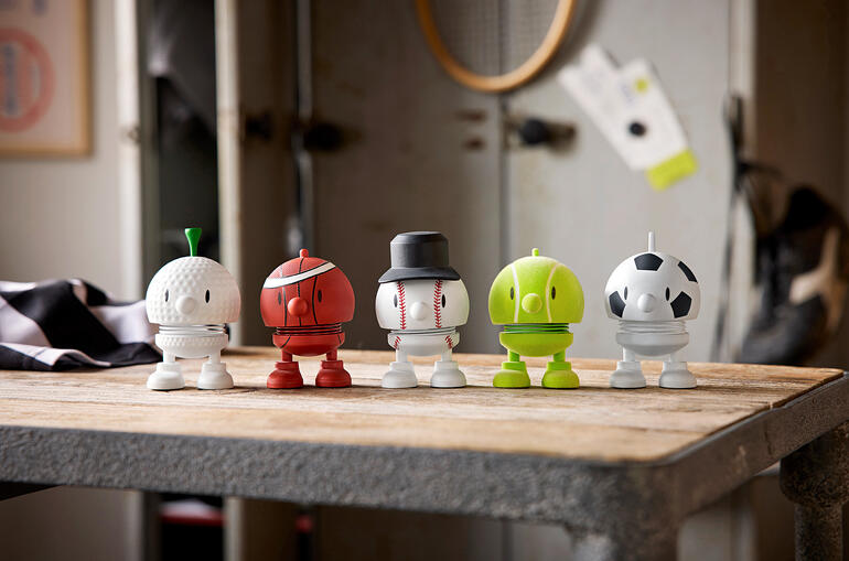 Cinq figurines Hoptimist dans différents designs sportifs sur une table.