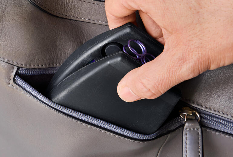 Idéal à emporter – par exemple pour l’entraînement au parc ou en voyage. Main prenant un entraîneur de torse compact dans un sac