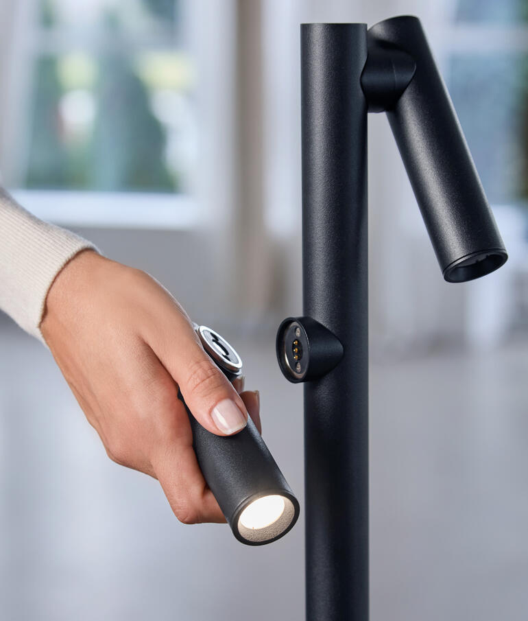 Main saisissant la lampe de poche du lampadaire pour un éclairage ciblé.