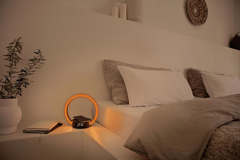 Réveil avec affichage lumineux rond sur une table de chevet.