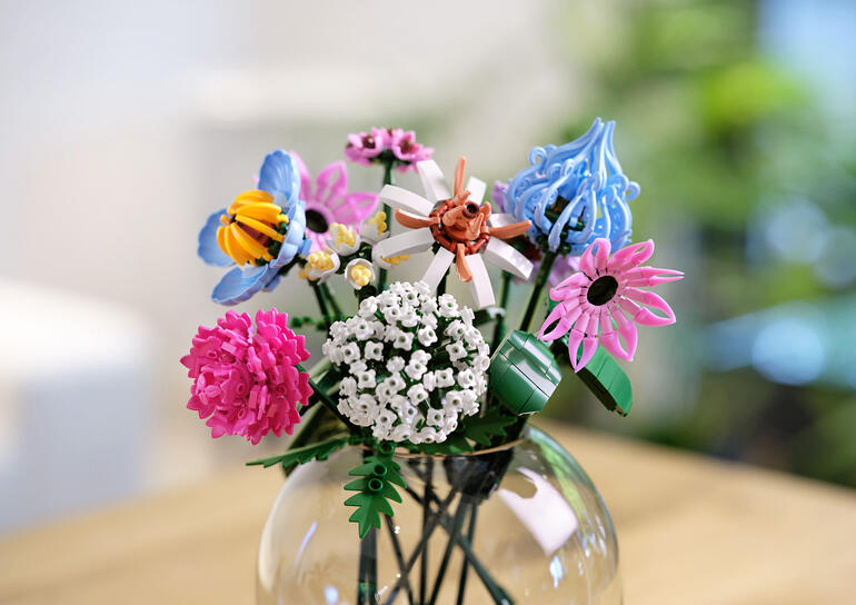 Bouquet de fleurs en briques de construction en teintes rose et violet dans un vase.