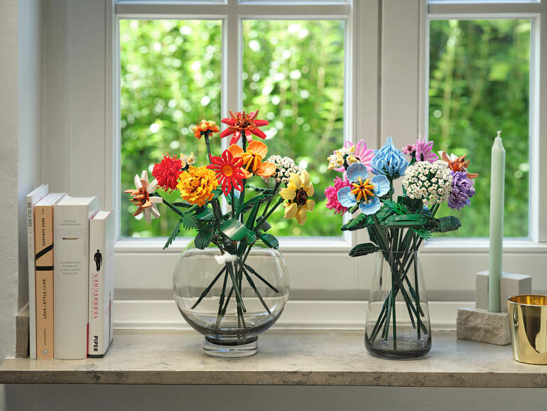 Il vous suffit d’assembler les pièces pour créer des bouquets d’une beauté intemporelle. Deux vases avec des fleurs colorées en briques de construction sur un rebord de fenêtre.