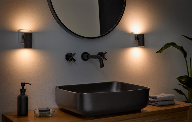Applique murale dimmable dans un environnement de salle de bain à côté d'un lavabo moderne.