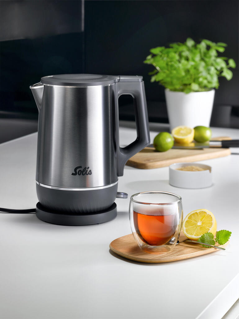 Bouilloire double avec finition en acier inoxydable et thé dans un bol en verre sur la table.