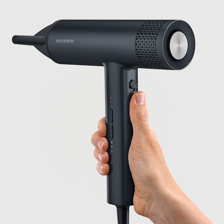 Gros plan d'un sèche-cheveux noir avec des commandes dans la main.
