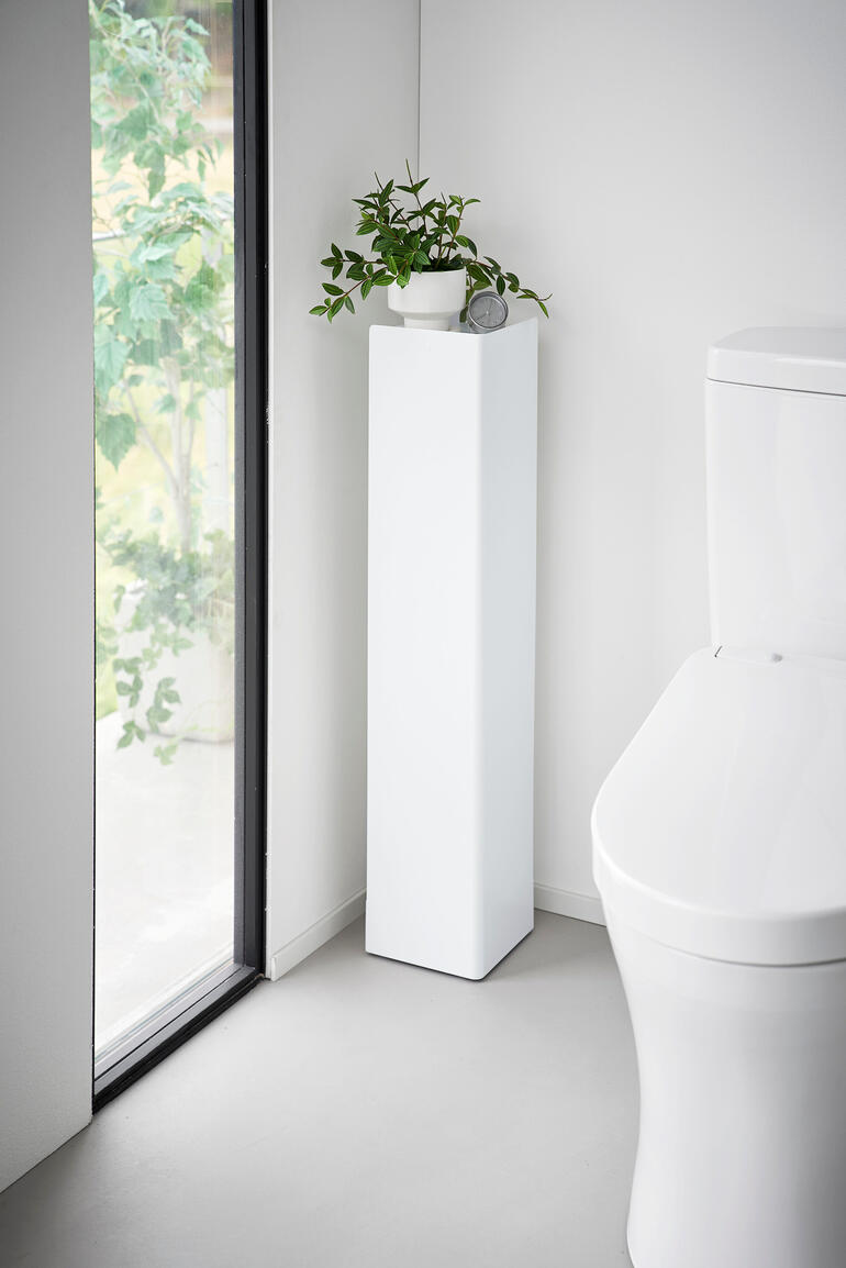 Organisateur de toilettes blanc avec plante et décoration dans le coin