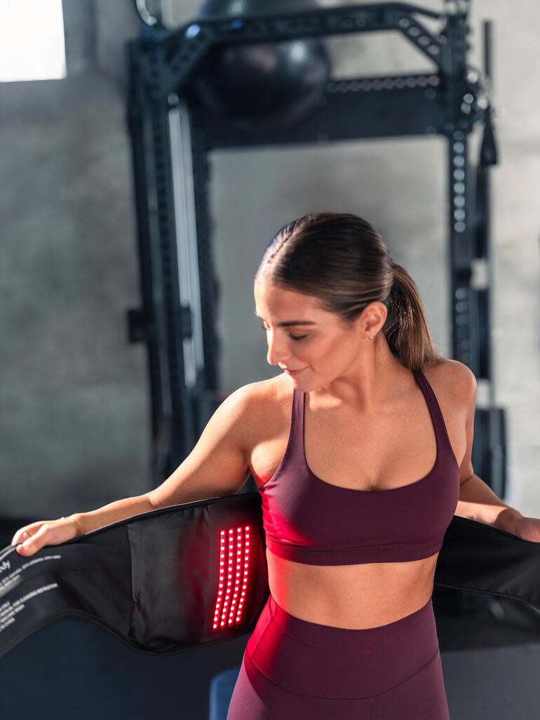 Femme avec une bande de dos 4-en-1 dans une salle de sport.