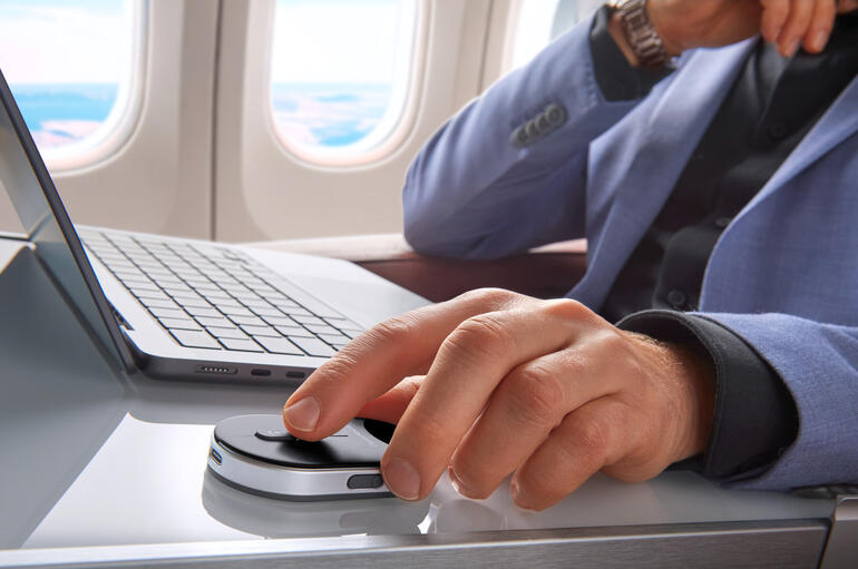 Homme dans un avion utilisant une souris mini sur une table.