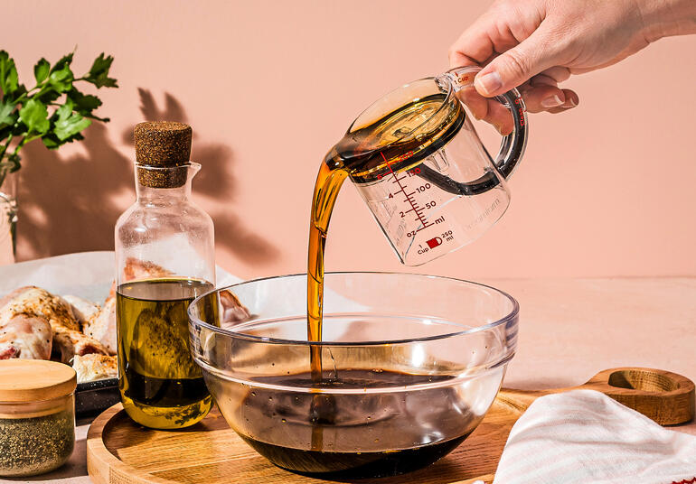 Personne versant de l'huile d'un verre mesureur dans un bol.