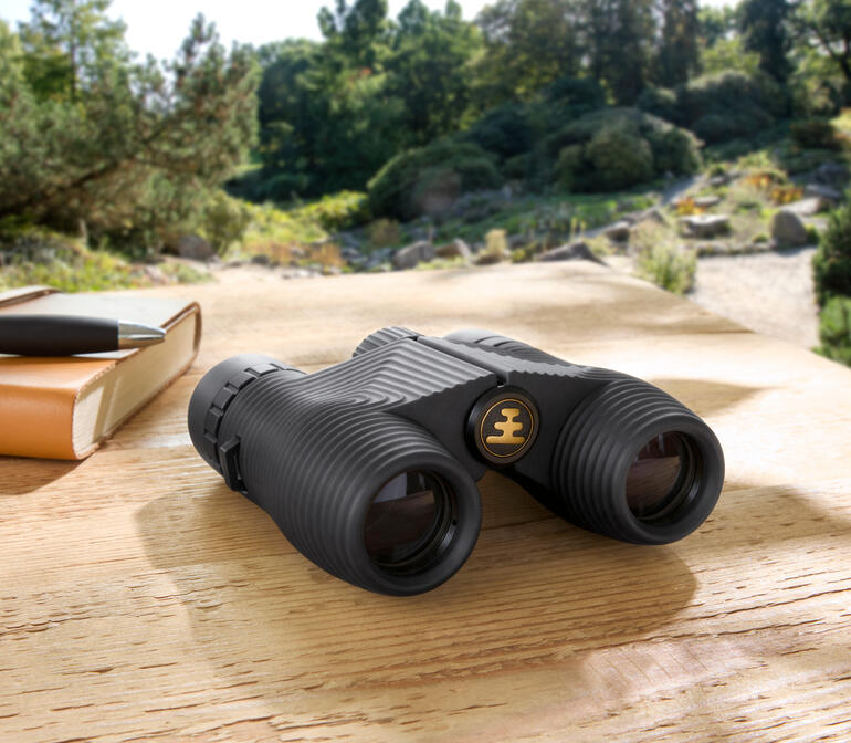 Jumelles compactes sur une table en bois dans la nature.