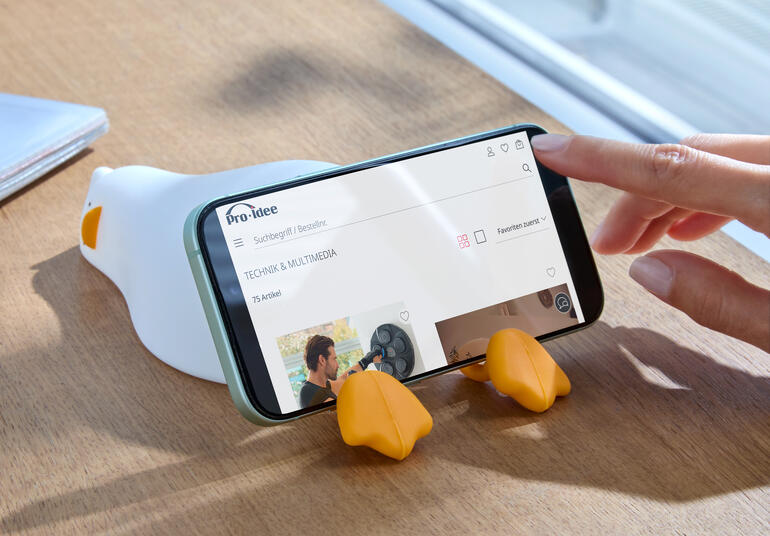 Canard fatigué veilleuse, sur une table à côté d'un smartphone.