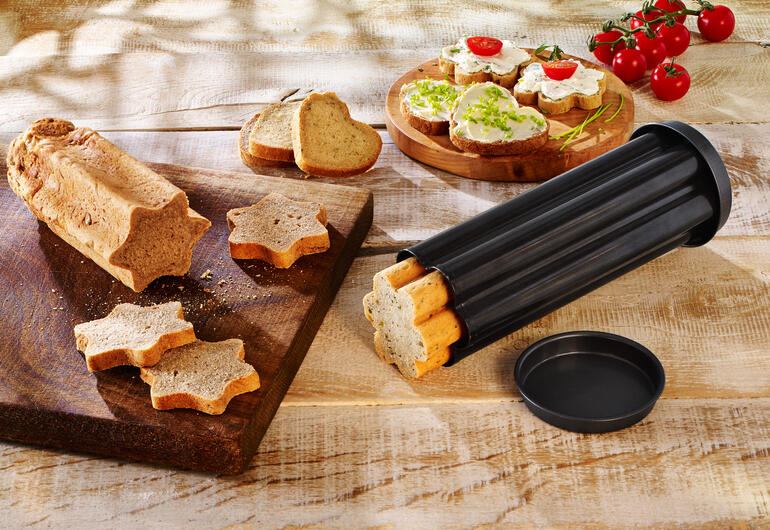 Trois tubes de cuisson pour pain de fête sur une planche en bois avec des formes de pain coupées et garnitures.