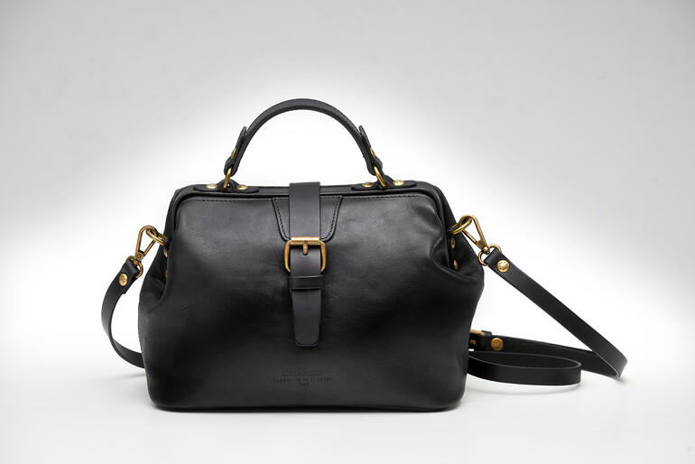 Sac à main noir pour dames en cuir structuré sur fond blanc.