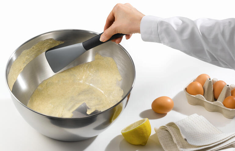 Spatule en silicone flexible qui prélève de la pâte d'un grand bol.