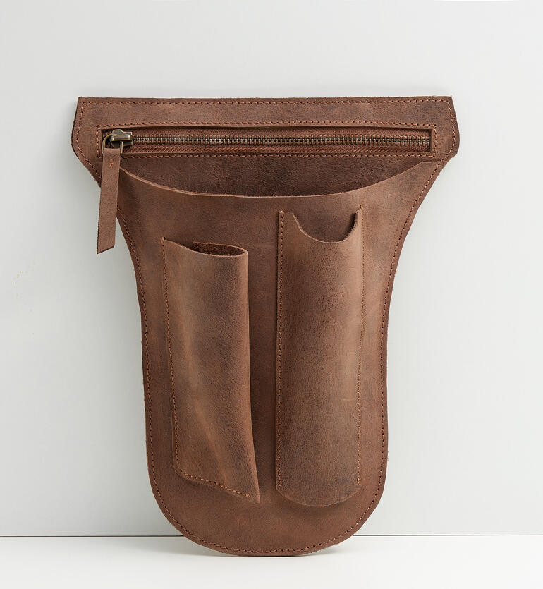 Ceinture à outils en cuir de buffle marron avec plusieurs poches sur fond gris.