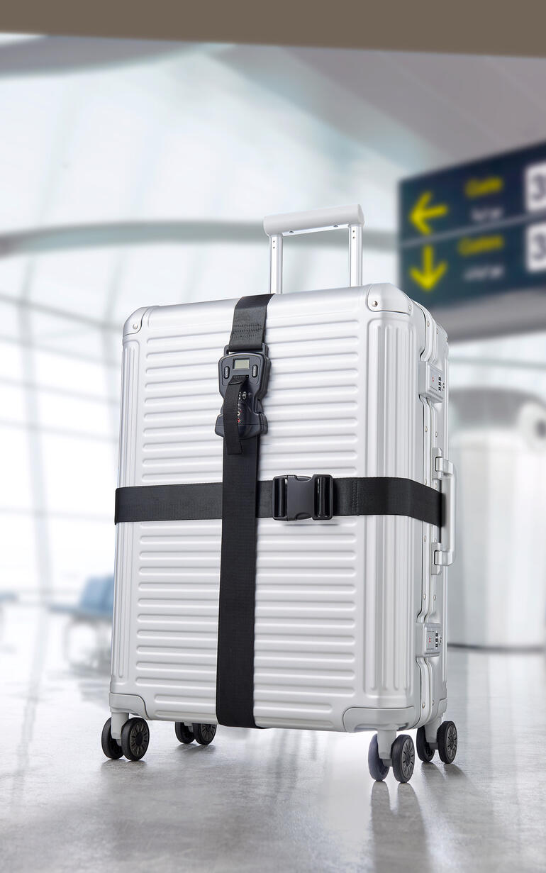 Valise argentée avec ensemble de ceintures de bagages noir 3-en-1 à l'aéroport.