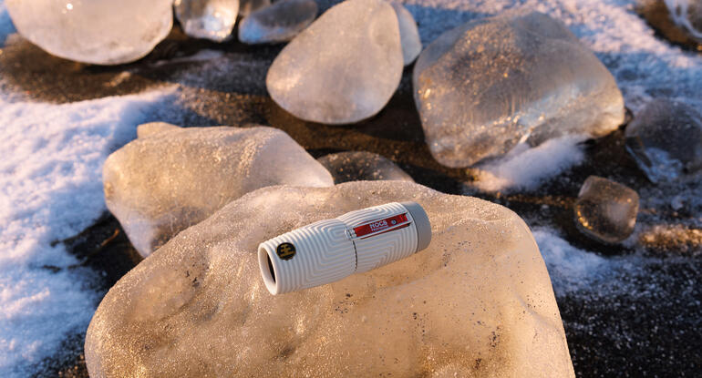 Monoculaire Nocs Provisions ZeroTube 10x25 sur un bloc de glace dans un paysage d'hiver.