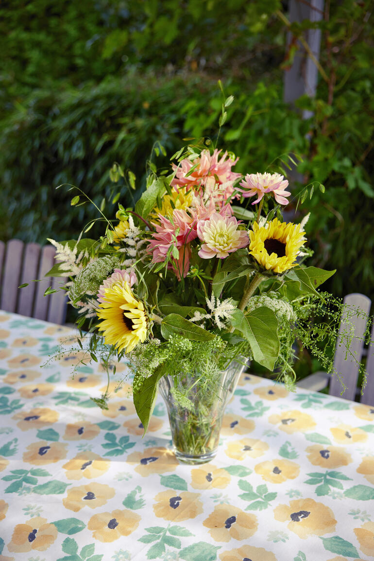 Table dressée avec une nappe aquarelle et un bouquet de fleurs.