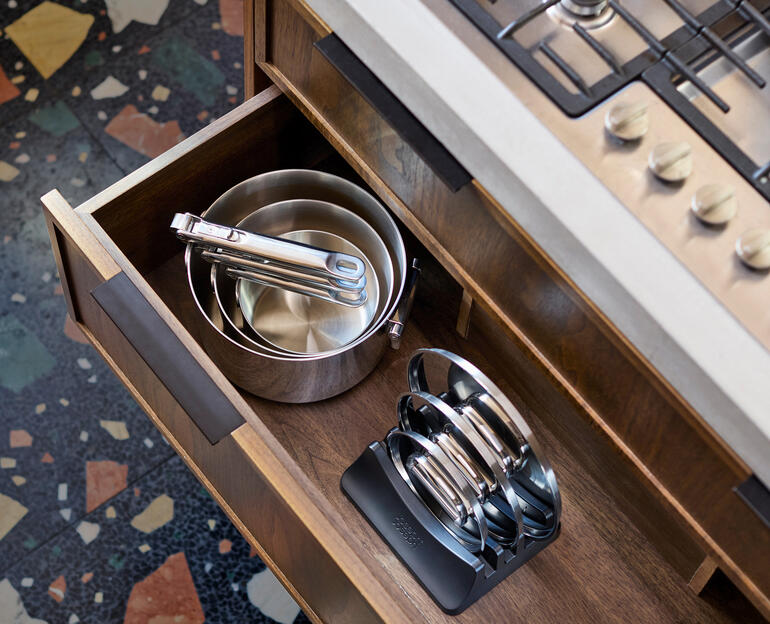 Ensemble de casseroles avec poignées pliantes dans un tiroir de cuisine, casseroles et couvercles visibles.