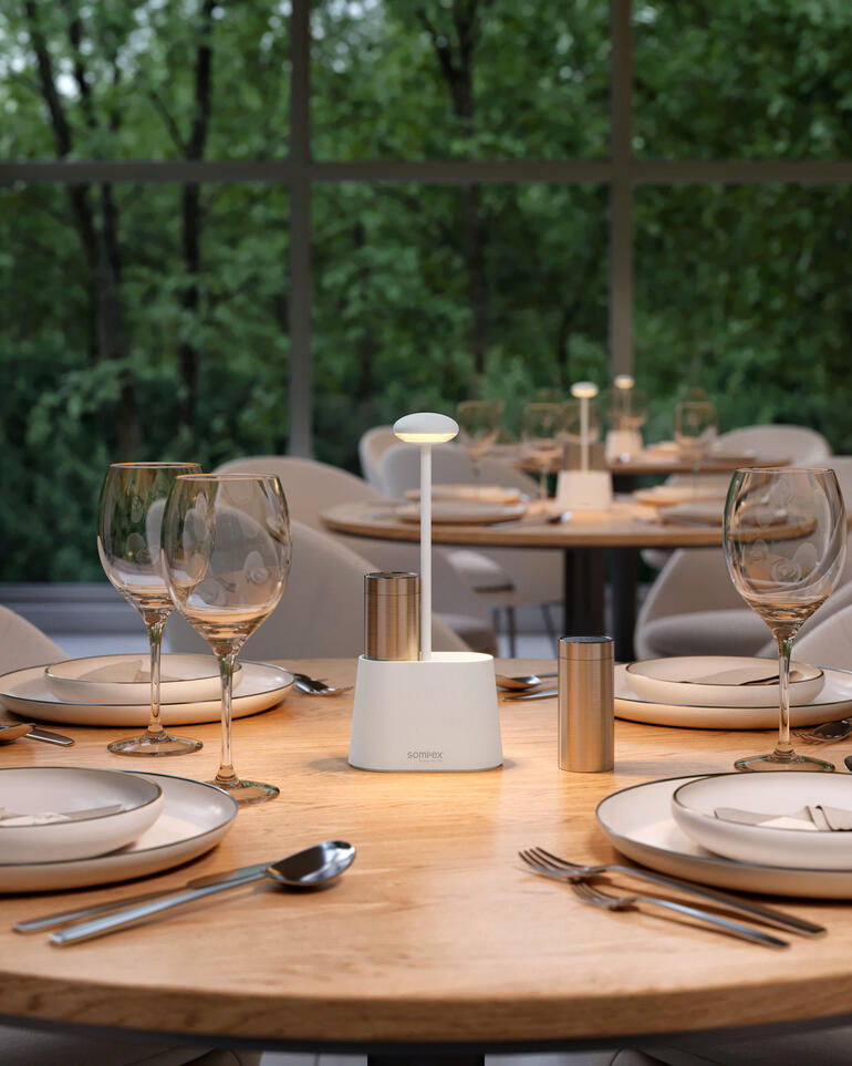 Lampe à poivre et sel blanche sur une table extérieure avec de la décoration.