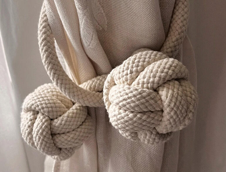 Deux nœuds d'une corde de porte en tissu épais sur un rideau.