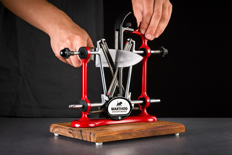 Aiguiseur de couteaux professionnel rouge utilisé par une main.