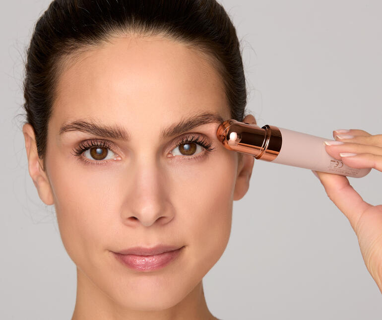 Femme tenant le rasoir facial Roxy contre son sourcil.