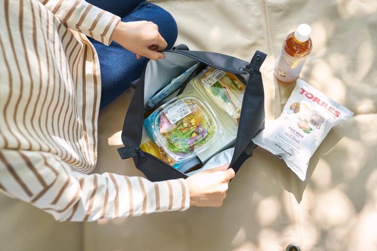Femme ouvrant un sac isotherme Vario et montrant des aliments frais à l'intérieur.