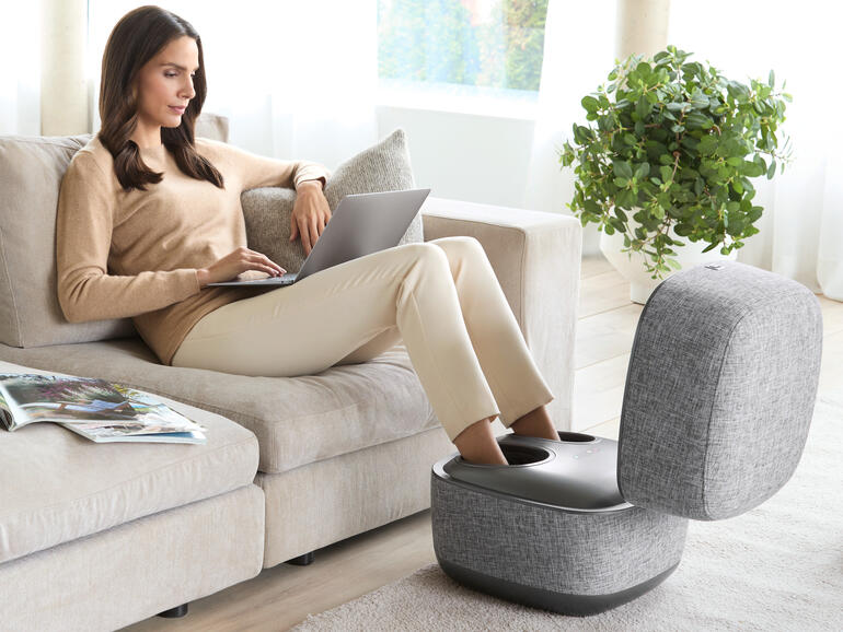 Femme se détendant avec un pouf de massage des pieds design.