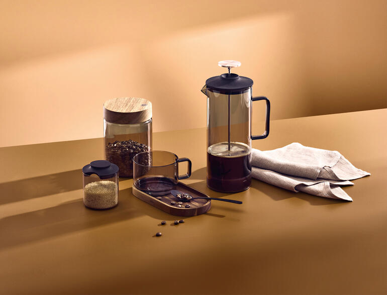 French-Press en verre soufflé à la bouche de 600 ml, grains de café et verres sur une table.