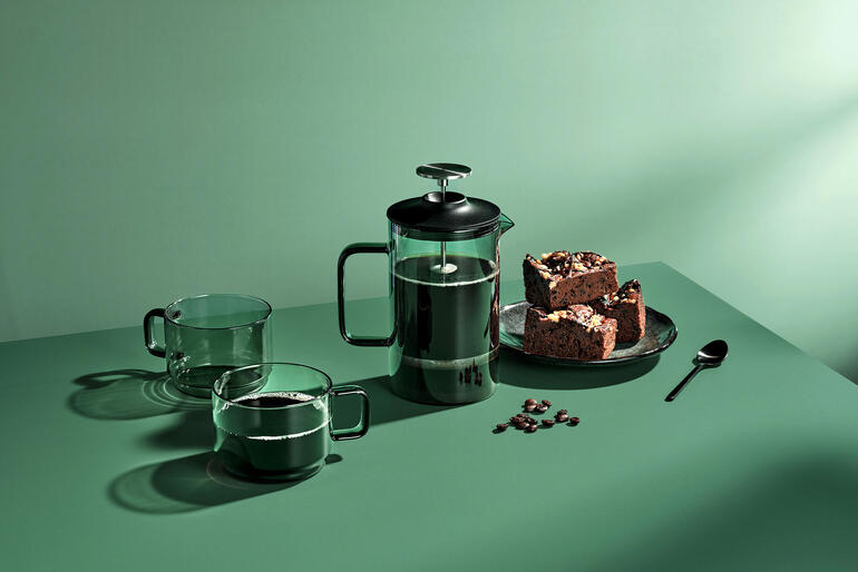 French-Press en verre soufflé à la bouche de 600 ml avec des biscuits au chocolat et des verres sur une table verte.