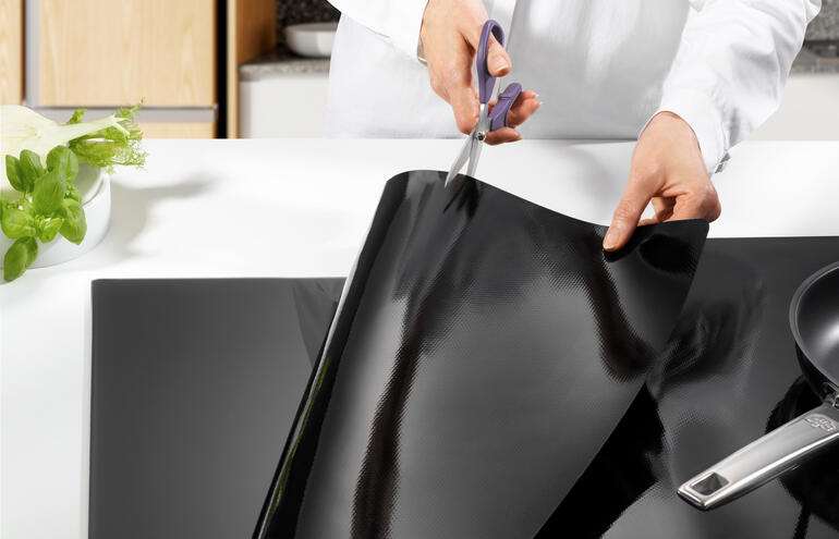 Quelqu'un découpe une protection de plaque à induction en platine