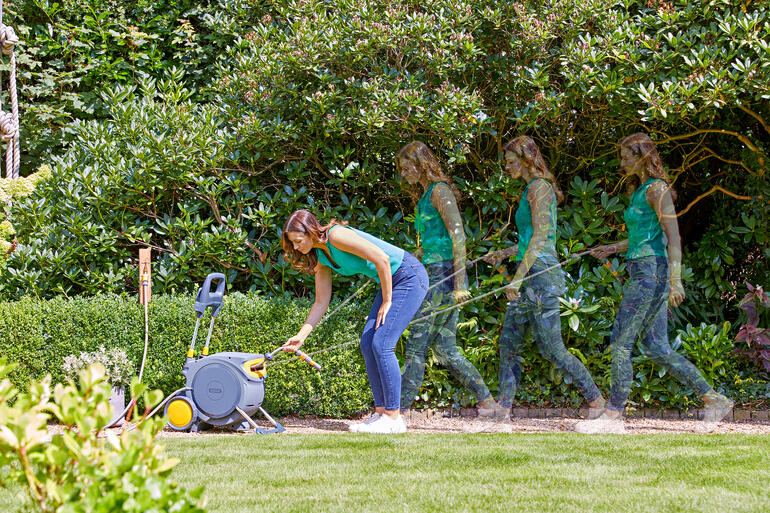 Femme utilisant un enrouleur de tuyau fermé pour arroser le jardin
