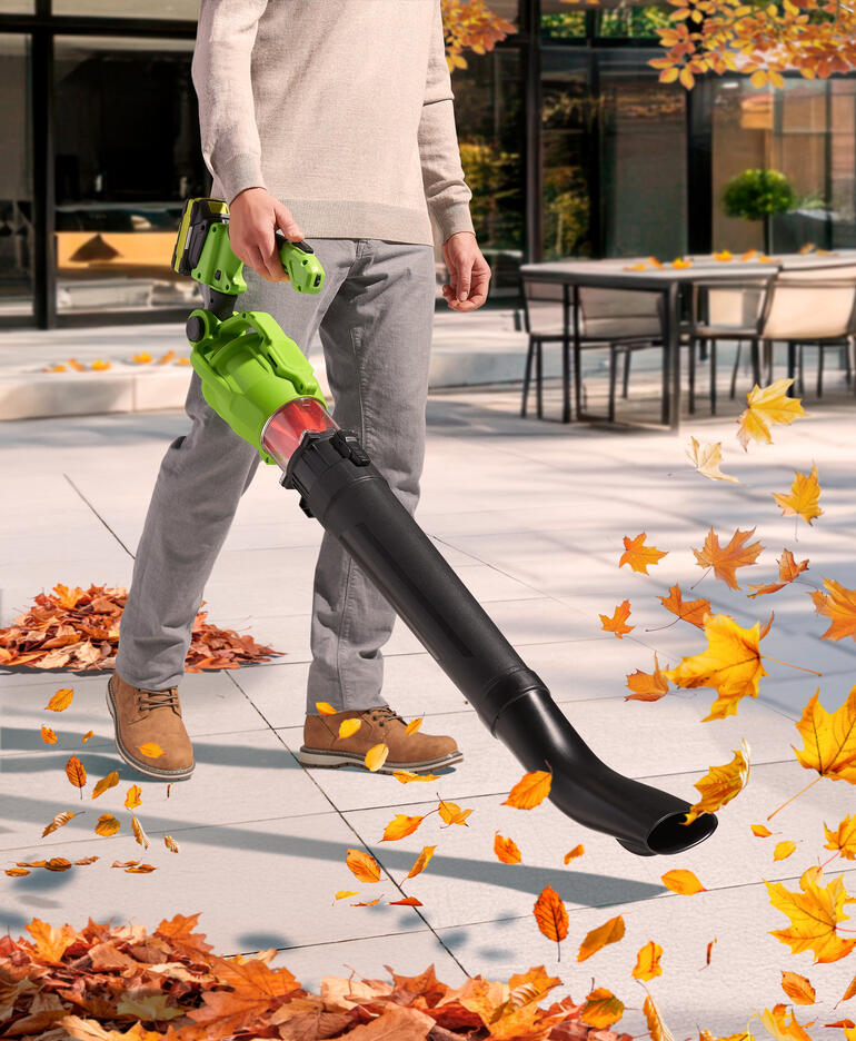 Homme utilisant un souffleur à feuilles télescopique sans fil sur la terrasse en automne.