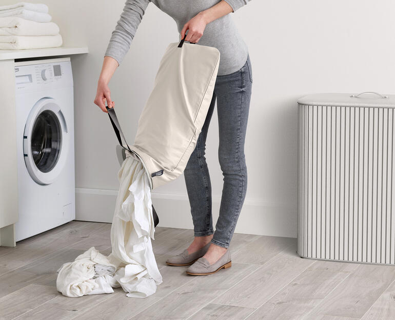 Femme vidant un collecteur de linge avec du linge sale.