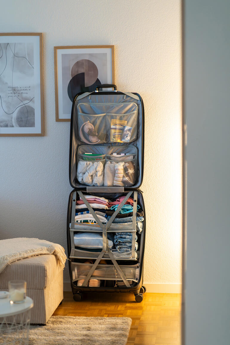 Valise dans la pièce, soigneusement remplie de vêtements.