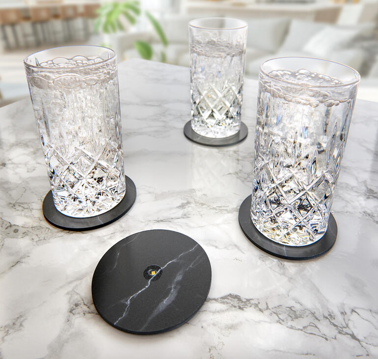 Trois verres sur un plateau en marbre avec des sous-verres noirs pour une expérience de boisson élégante.