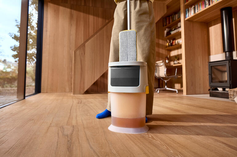 Robot de nettoyage avec seau sur un sol en bois.