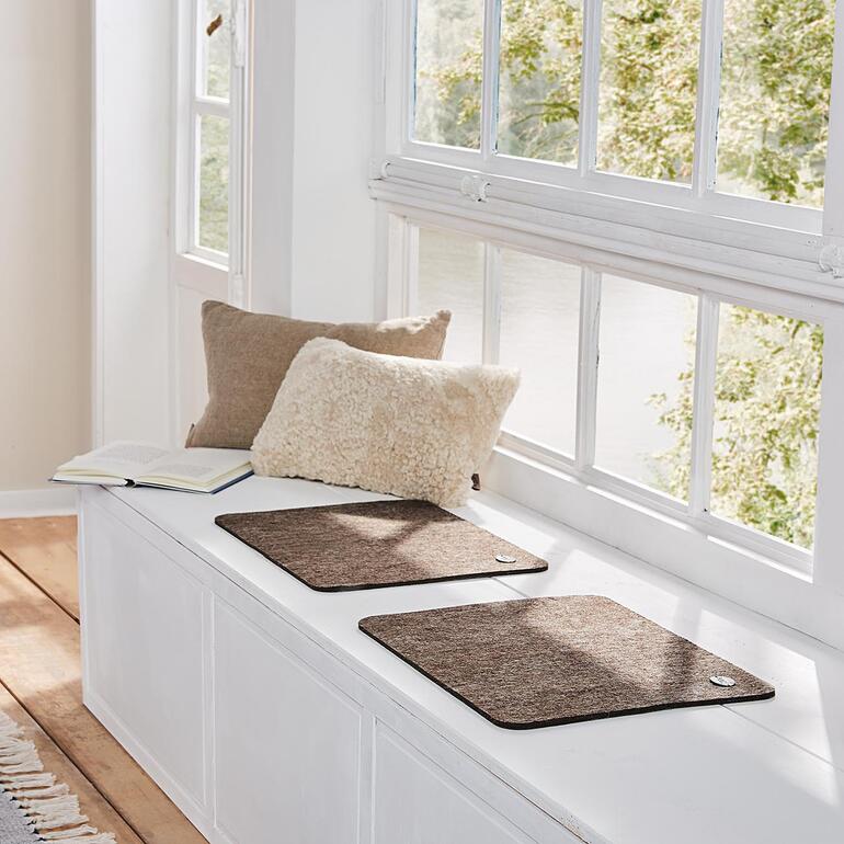 Deux coussins de siège en alpaga brun clair sur un rebord de fenêtre.