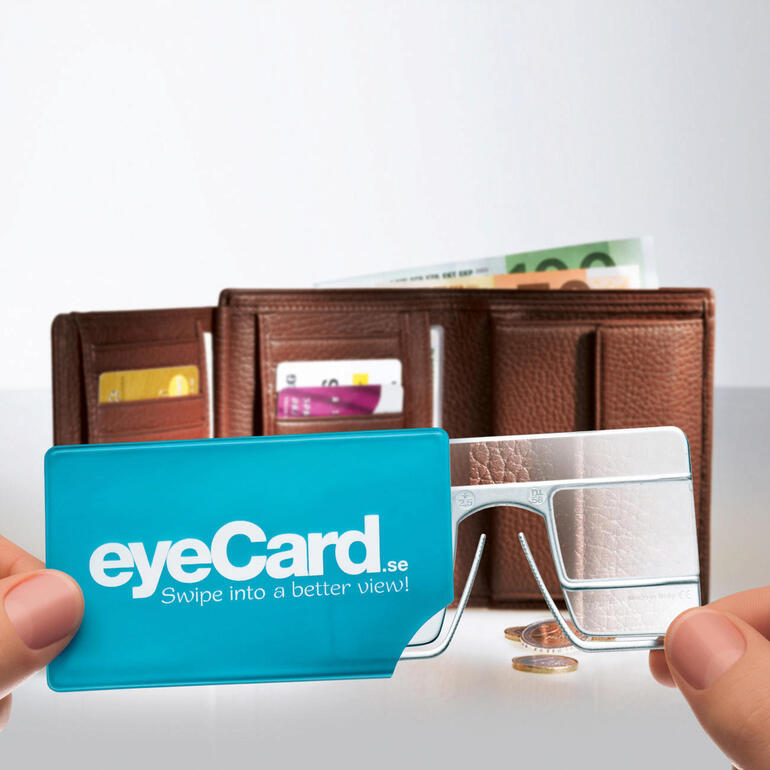 Rangée dans son étui en plastique pratique, votre eyeCard® vous accompagnera partout où vous allez. eyeCard® ensemble de 2 à côté d'un portefeuille