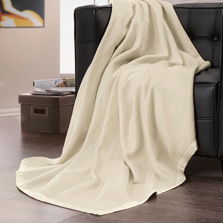 Couverture en fleece de soie dans des teintes beige douces sur un canapé