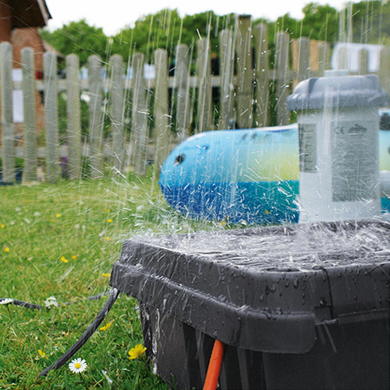 Avec un indice de protection élevé IP 55, la DRi®BOX protège de la poussière et de la pluie à 100 %. DRi®BOX touché par des éclaboussures d'eau sur une pelouse.