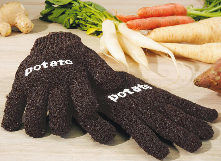 Lavez les carottes, des rutabagas, des branches de céleri, les pommes etc. Aussi simple que de se laver les mains. Gants à pommes de terre pour enfants ou adultes sur une table en bois.