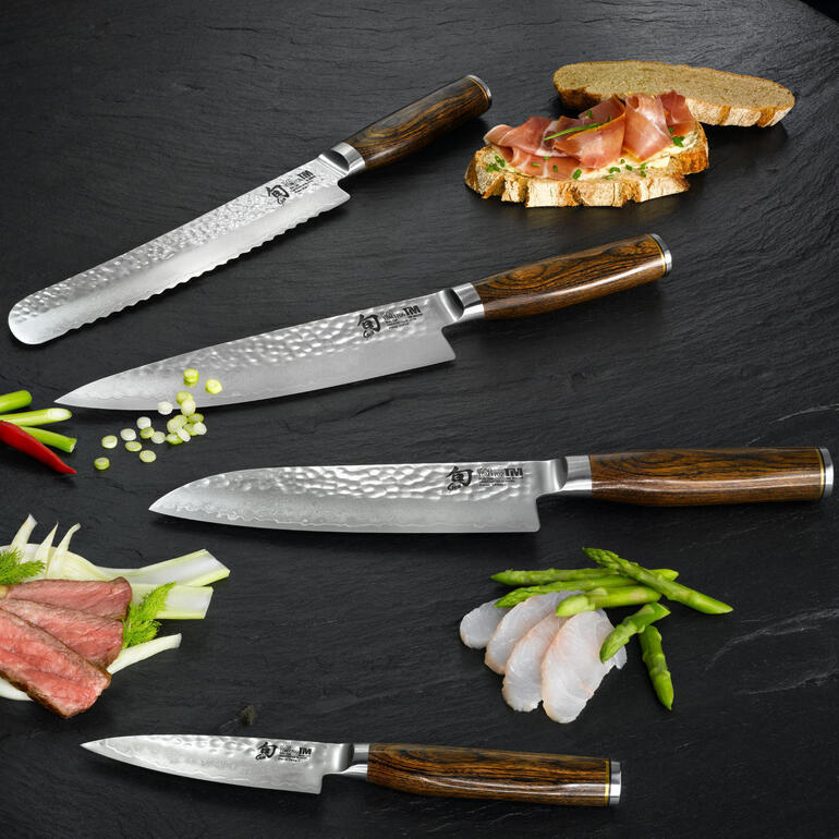 Couteaux Shun Premier « Tim Mälzer » Différents couteaux Shun Premier sur fond noir, y compris un couteau à jambon et un couteau à pain.