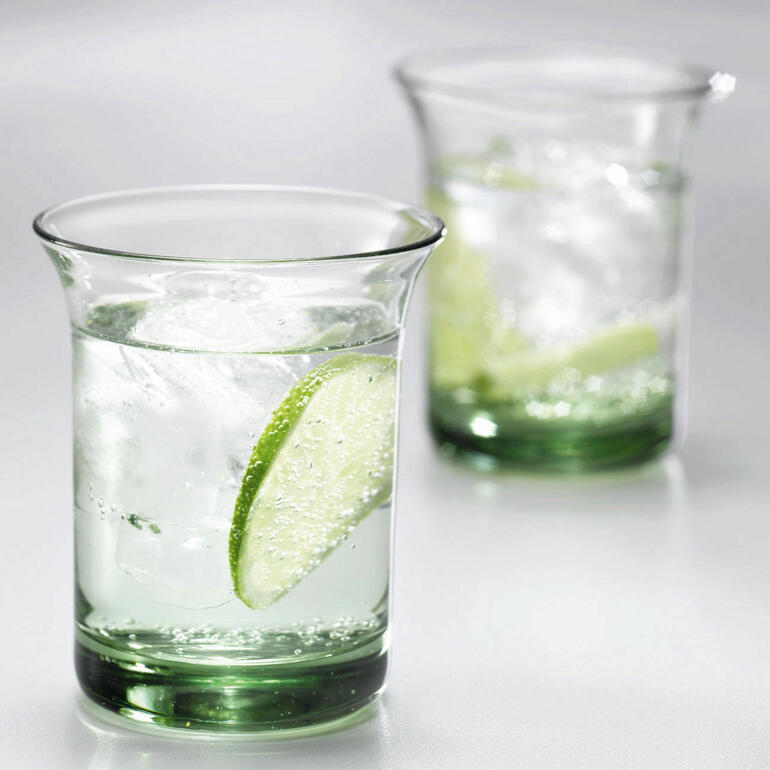 Deux verres d'eau Goethe avec des glaçons et des rondelles de citron vert sur une table.