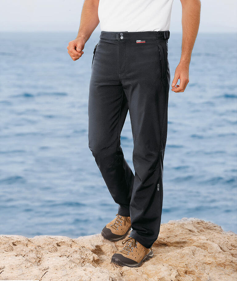 Homme portant un pantalon softshell noir au bord de la mer.